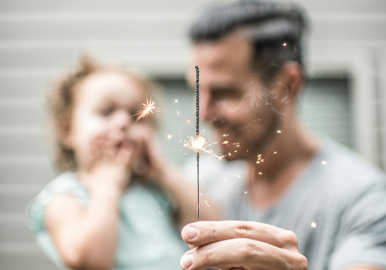 Man holding daughter and sparkler